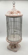 A large ceramic bird cage with floral decoration on footed base