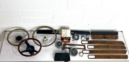 Three vintage steering wheels, along with a selection of gauges and some Jaguar wood panel trim.