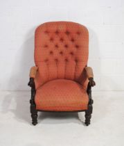 A Victorian mahogany framed upholstered armchair, with button-back detailing and carved decoration