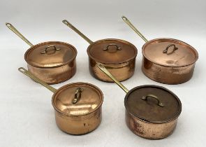 A collection of five copper saucepans