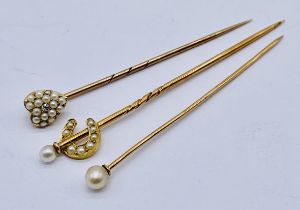 Three unmarked gold tie/stock pins including a heart shaped pin set with a diamond and seed pearls