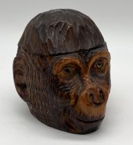 A turn of the century novelty treen inkwell fashioned as a monkey/gorilla head with glass eyes,