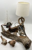 A collection of various items including lamp with coiled rope base, wooden boats, cast iron bird