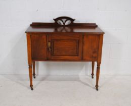 A turn of the century sideboard of small proportions, with single cupboard, raised on turned