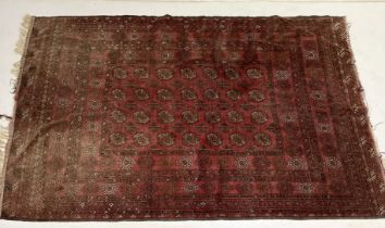 A large Eastern red ground rug with repeated pattern, fading as shown - 290cm x 205cm