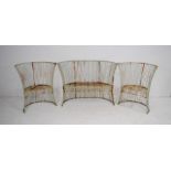 A weathered three piece curved metal garden suite, comprising a bench and two chairs