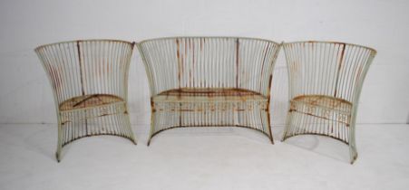 A weathered three piece curved metal garden suite, comprising a bench and two chairs