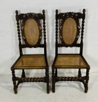 A pair of turn of the century oak carved dining chairs with cane seats, one has slight damage to