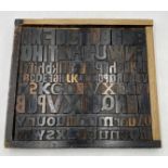 A wooden tray containing a collection of vintage letterpress wooden printing blocks