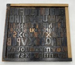 A wooden tray containing a collection of vintage letterpress wooden printing blocks