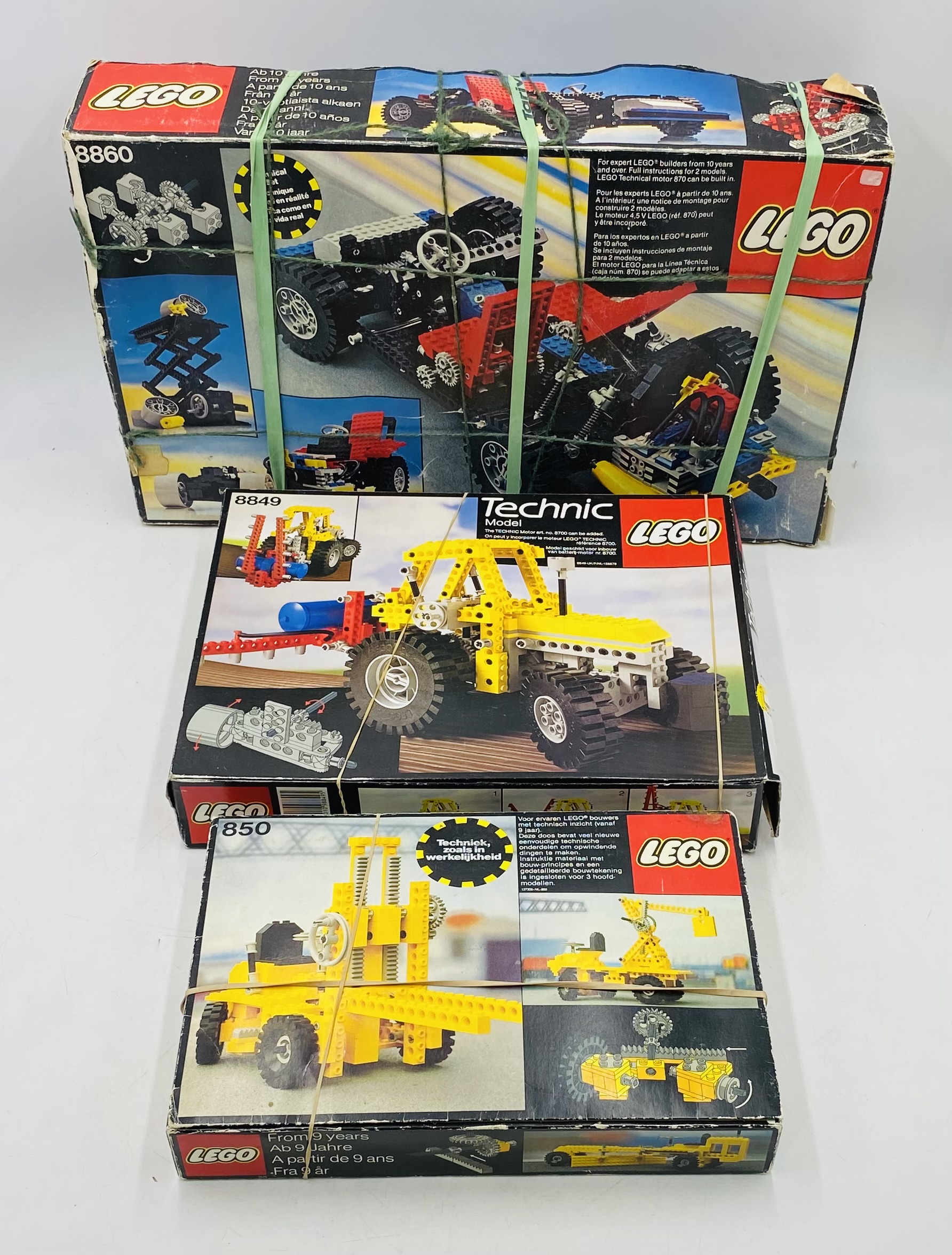 Three boxed vintage Lego Technic sets including Car Chassis (8860), Tractor (8849) and Forklit (850)