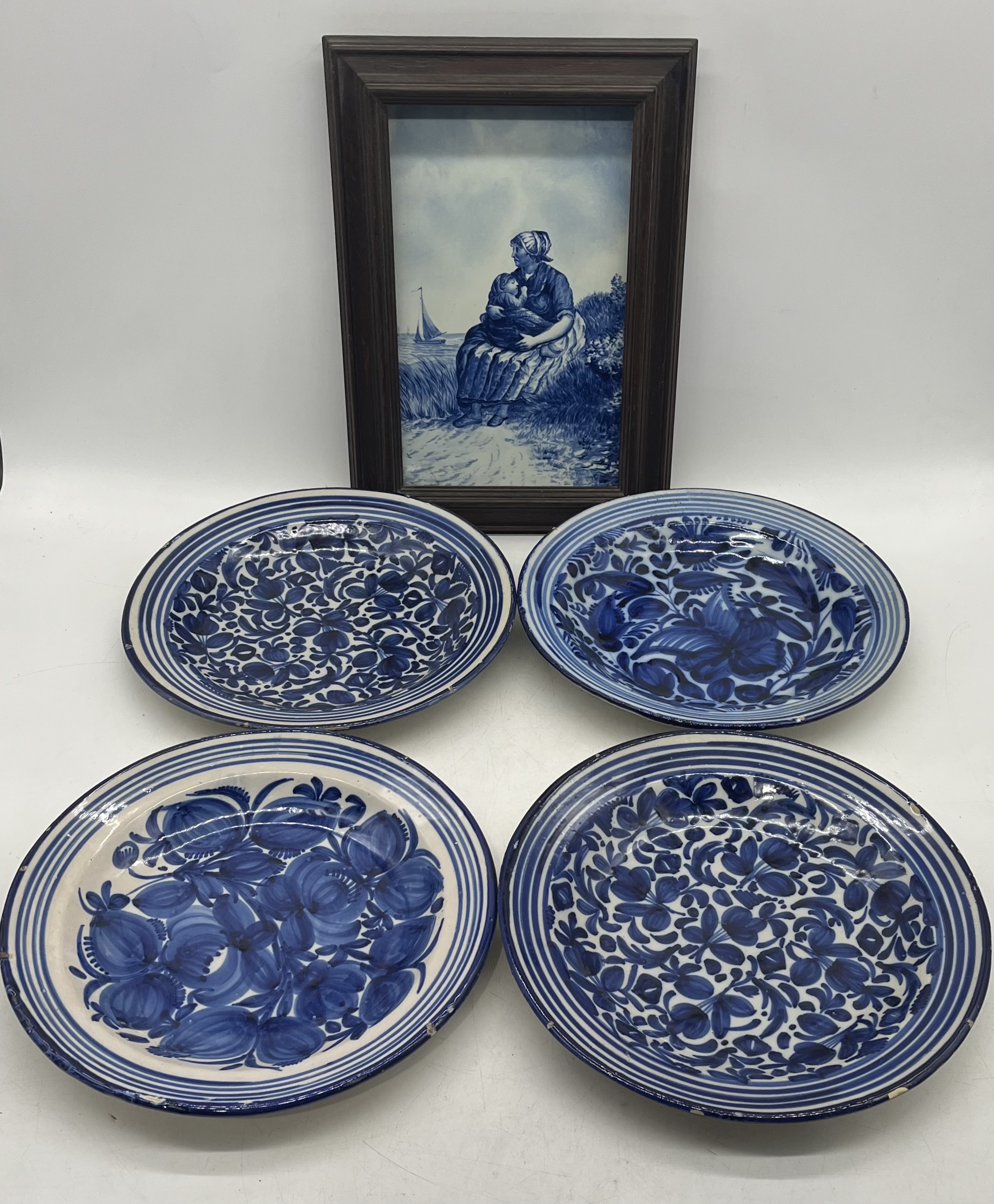 A Delft plaque (frame in need of attention) along with four blue and white chargers (some chips to