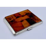 A continental silver cigarette case (835) the front set with a patchwork of amber, total weight