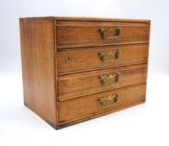An oak table-top chest of four drawers, with brass handles, marked 'Henry Stone & Son' of