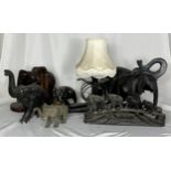 A collection of various elephant figures including a wooden carved lamp with a cobra, elephant