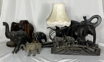A collection of various elephant figures including a wooden carved lamp with a cobra, elephant