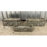 A pair of weathered reconstituted stone garden troughs with lion motif along with one other