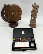 A turned wooden clock along with an artist's box and carved Eastern figure