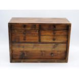 A table-top pine chest of eight drawers, containing various clock parts - length 51cm, depth 23cm,