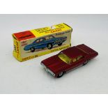 A vintage boxed Dinky Toys Pontiac Parisienne die-cast car in metallic red with a yellow interior (