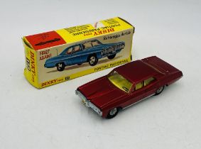 A vintage boxed Dinky Toys Pontiac Parisienne die-cast car in metallic red with a yellow interior (