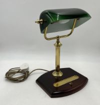 A modern banker's lamp with green shade and pen tray