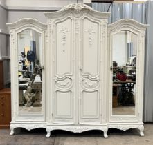 A French classical style white painted triple wardrobe, with mirrored doors and ornate detailing -