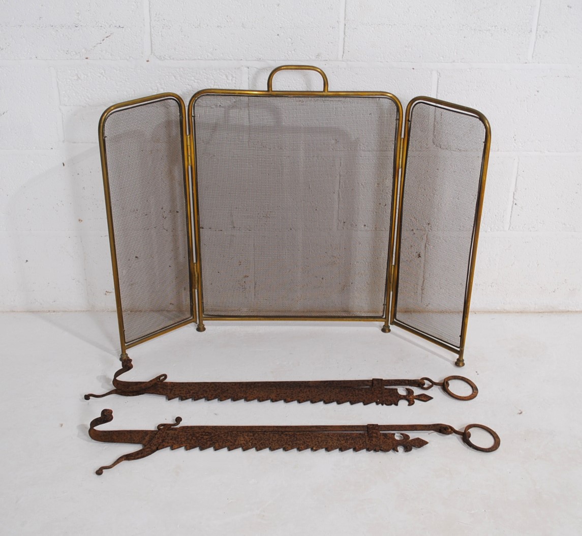 A pair of antique chimney crooks, along with a brass folding fire guard