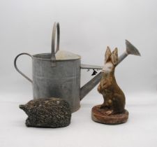 A galvanised watering can, along with two reconstituted stone garden figures of a hedgehog and a