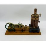 A vintage live steam engine with vertical boiler, mounted on a wooden plinth - overall length 46cm