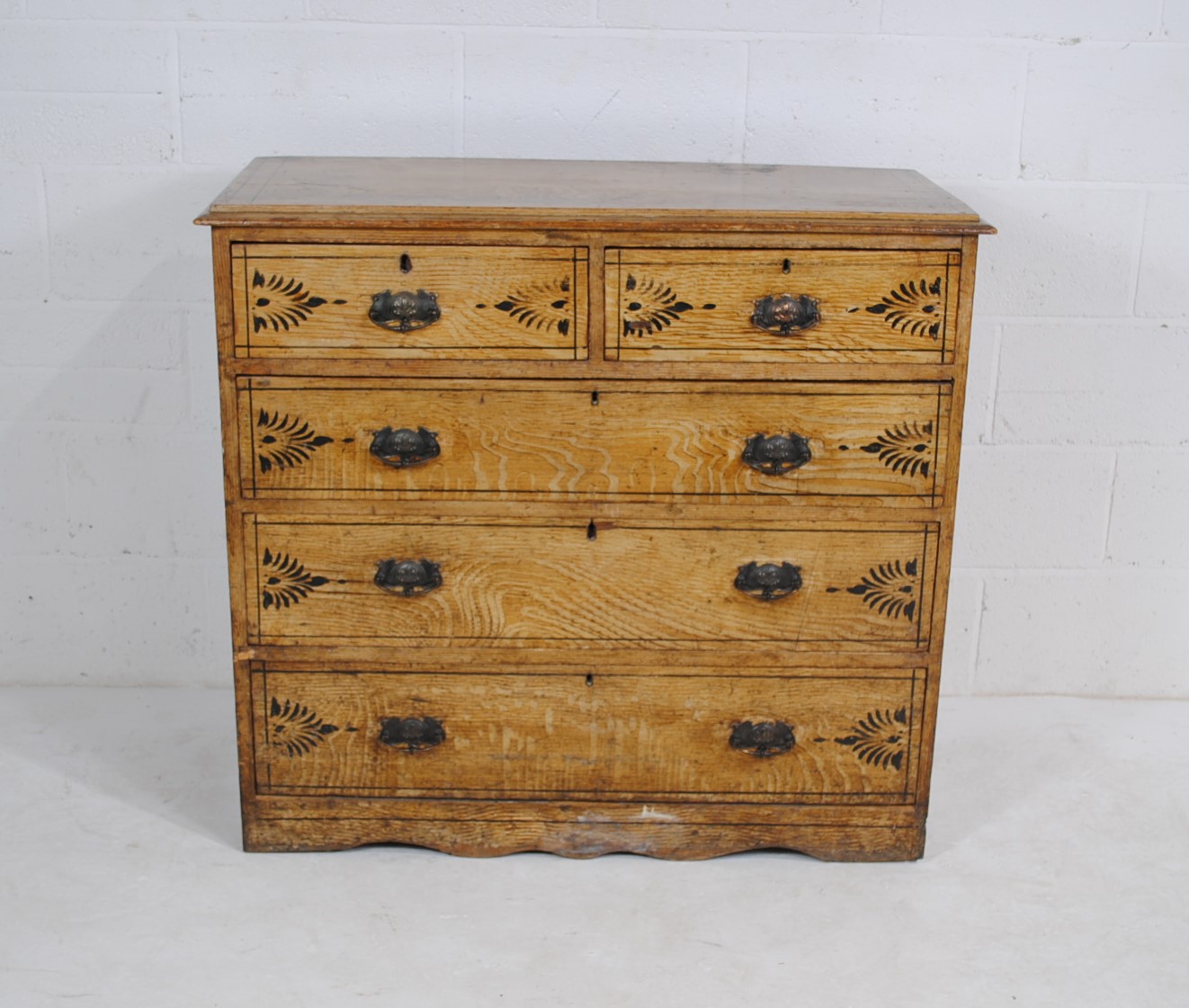 An antique pine chest of five drawers, with painted decoration and metal Art Nouveau handles -