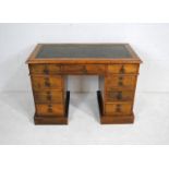 A Victorian oak kneehole writing desk, with green leather inset top and nine drawers - length 106cm,