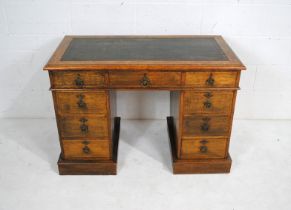 A Victorian oak kneehole writing desk, with green leather inset top and nine drawers - length 106cm,