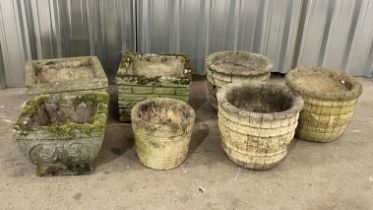 A collection of weathered reconstituted stone garden pots including three matched planters with