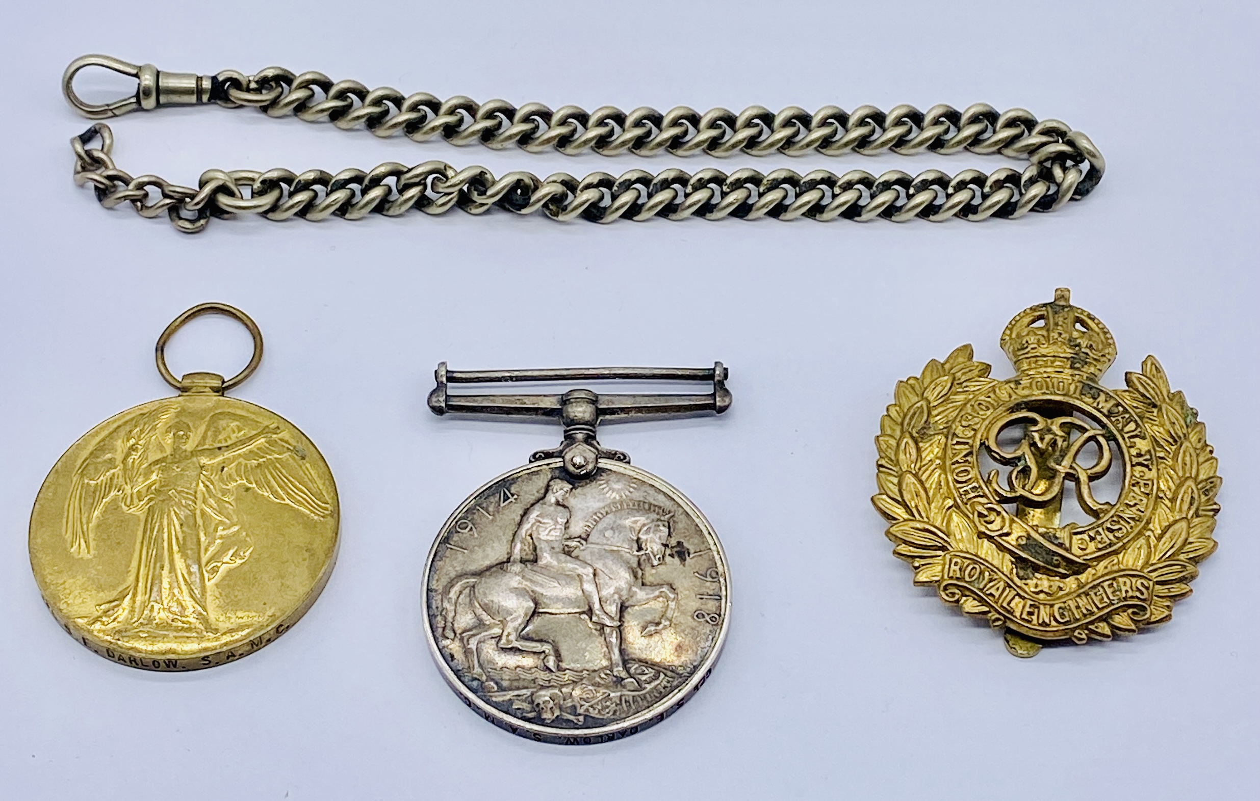 Two WWI medals awarded to Cpl. S E Darlow, SAMC along with a Royal Engineers cap badge