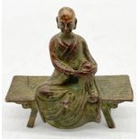 A small bronze figure of Buddha seated on a bench