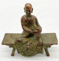 A small bronze figure of Buddha seated on a bench