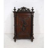 A turn of the century heavily carved oak wall hanging cupboard, with barley twist supports, with key