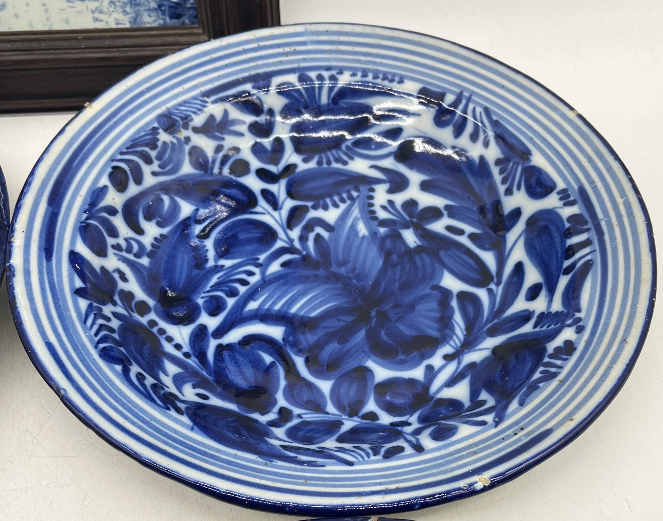 A Delft plaque (frame in need of attention) along with four blue and white chargers (some chips to - Image 4 of 8