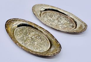 A pair of hallmarked silver pin dishes decorated with cherubs