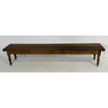 A long pitch pine bench on turned legs - length 275cm, width 46cm