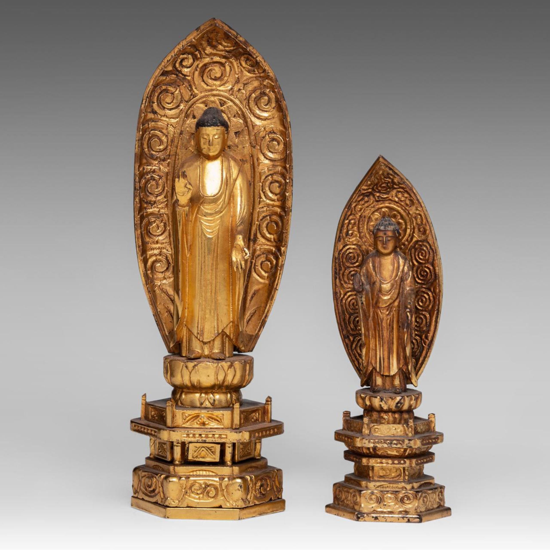 Two Japanese gilt lacquered figures of standing Buddha, late 19thC/ 20thC, H 24,5 - 33 cm