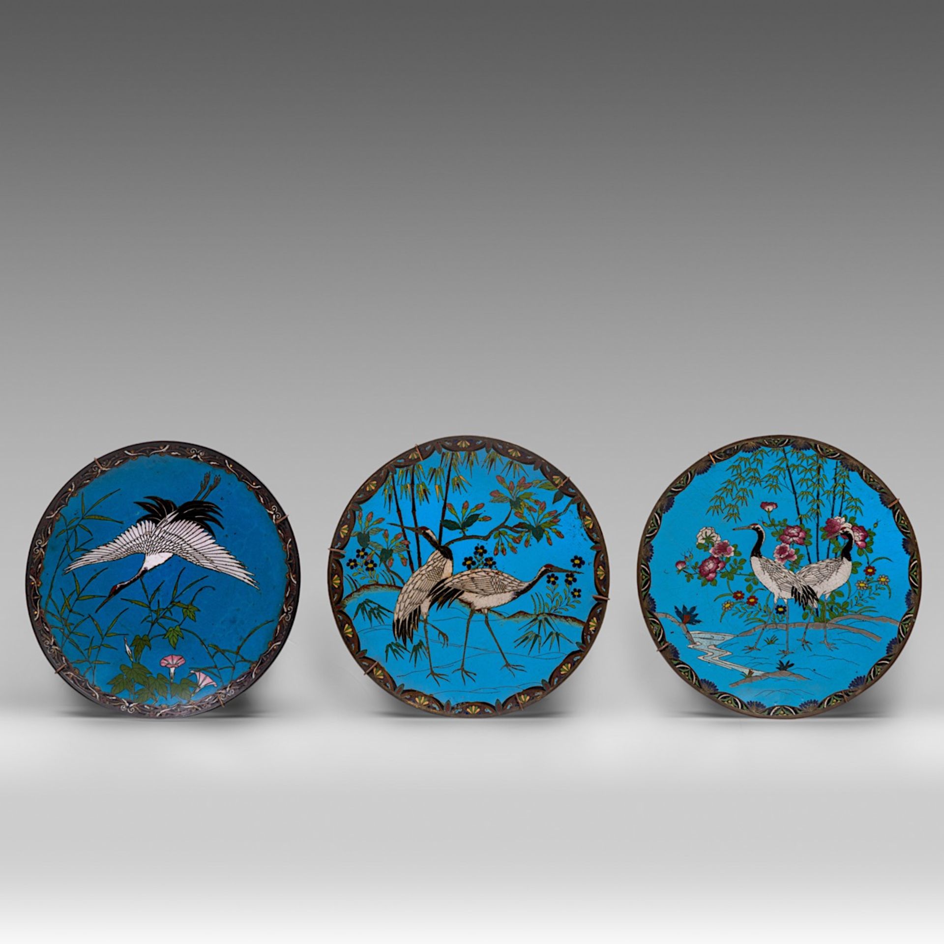 A matching assembled set of three Japanese cloisonne enamelled dishes with scenes of cranes, late Me