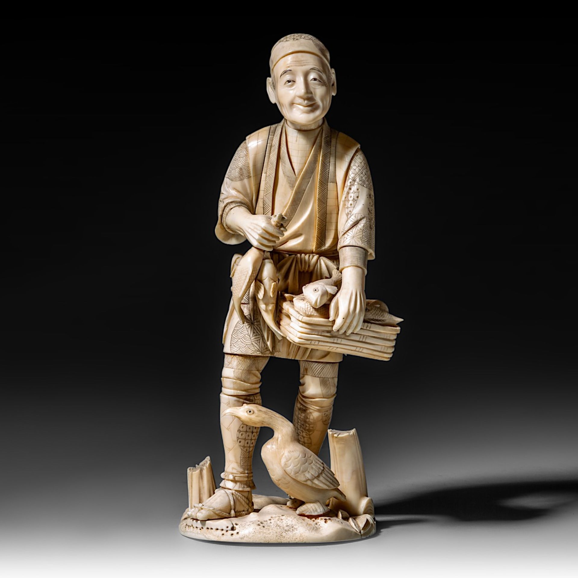 A Japanese hippo and walrus ivory okimono of a man selling fish, Meiji period (1868-1912), H 28,5 cm