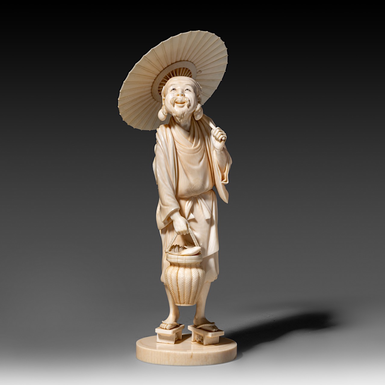 A very fine Japanese ivory okimono of a man with an umbrella, Tokyo school, Meiji period, H 23 cm -