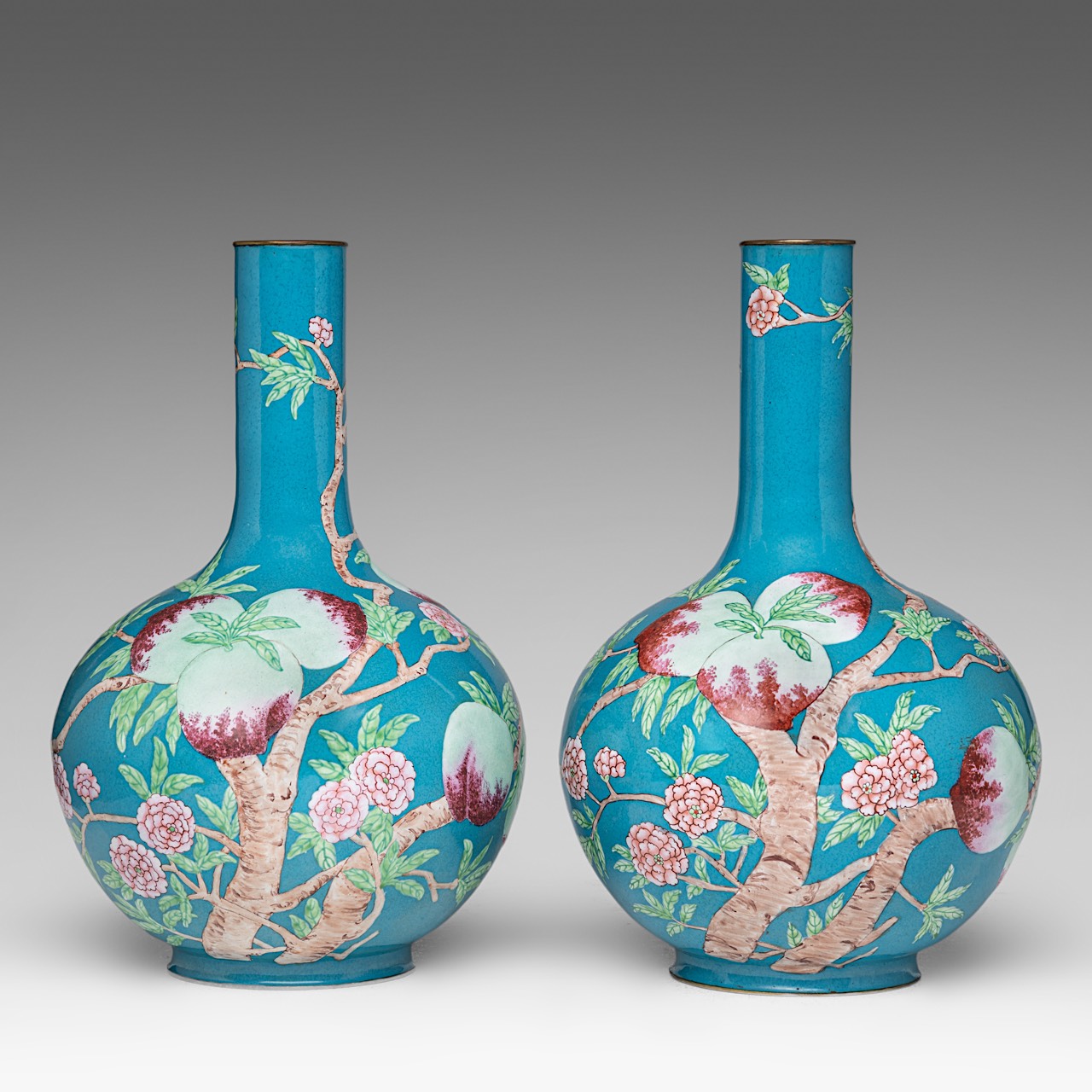 A fine pair of Chinese turquoise ground Canton enamel on copper 'Nine Peaches' bottle vases, late Qi