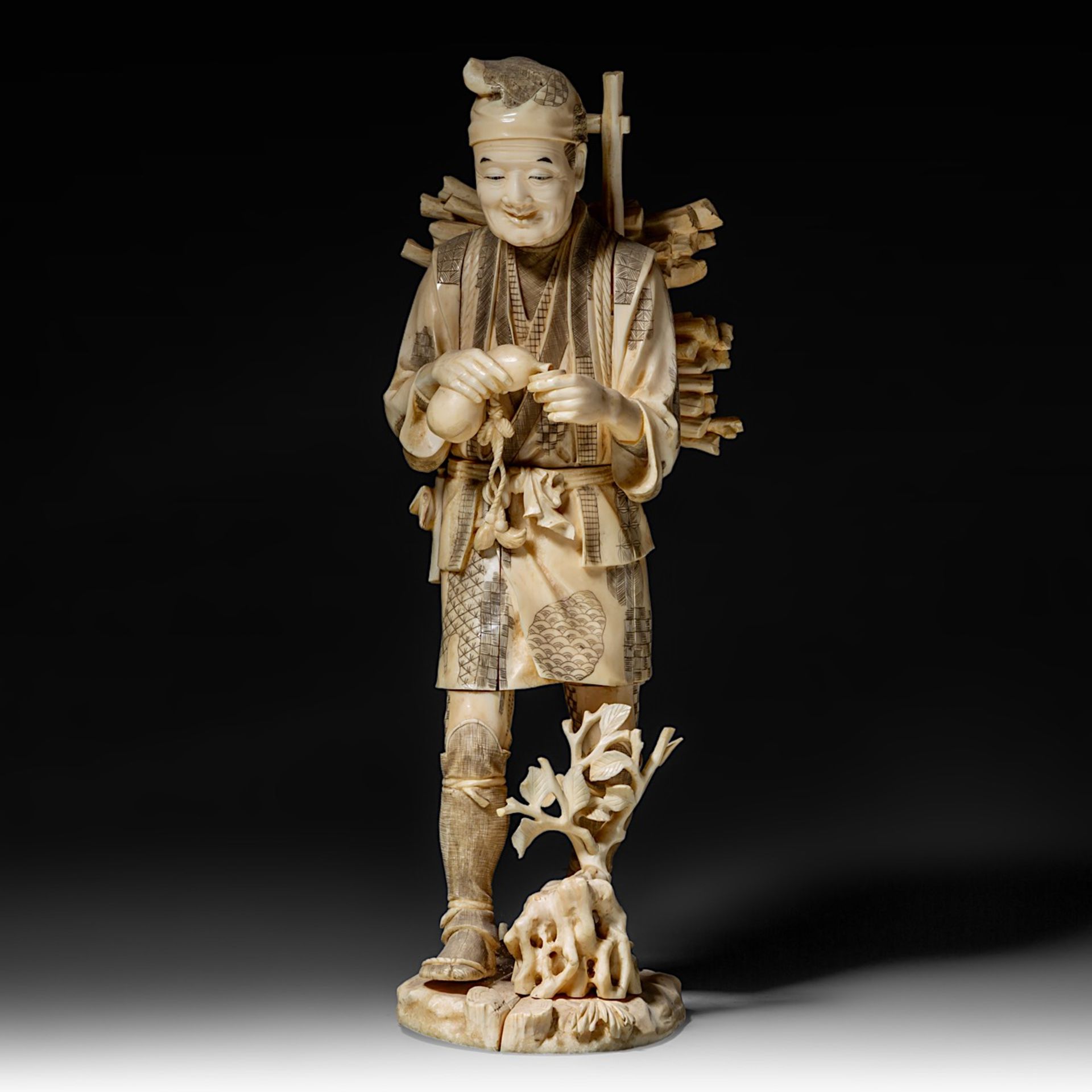 A large Japanese walrus ivory okimono of a wood gatherer drinking from a gourd flask, Meiji period (