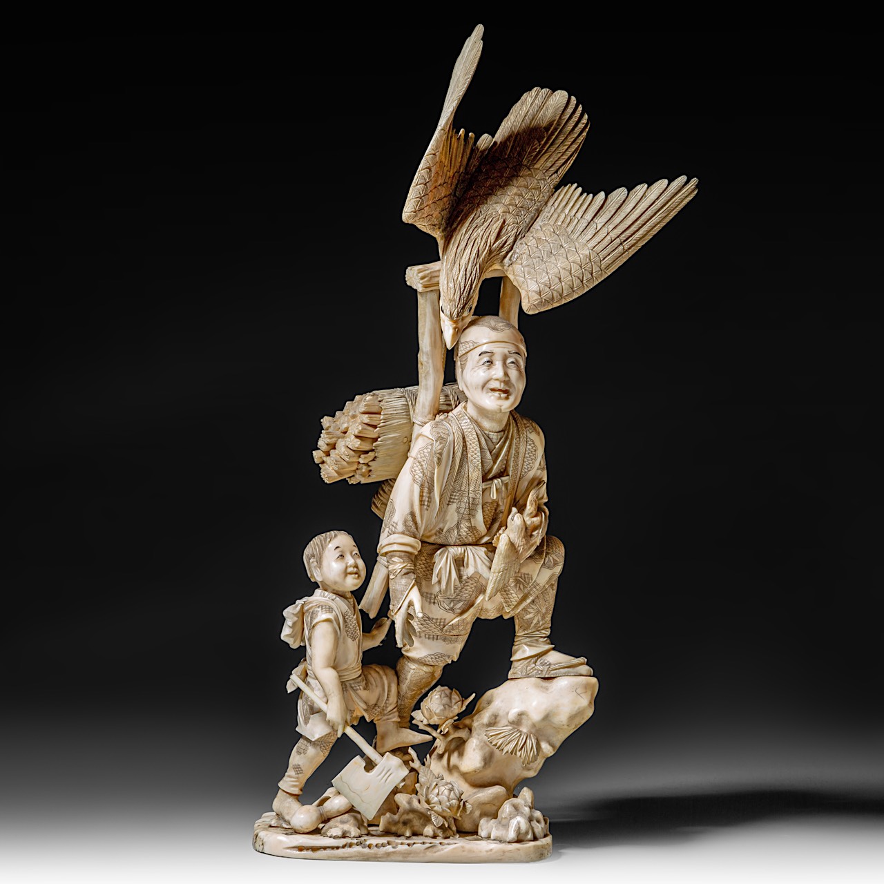 A large and fine Japanese walrus ivory okimono of a falconer and his son watching an eagle, Meiji pe