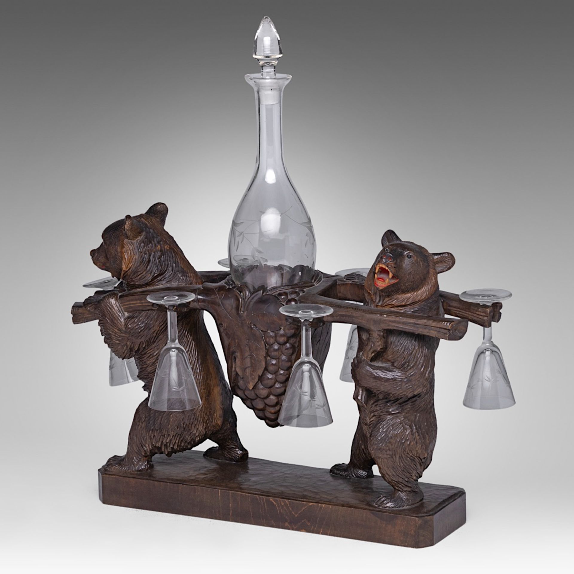 A Black Forest carved wooden liquor stand with two bears carrying the decanter and six glasses, H 4