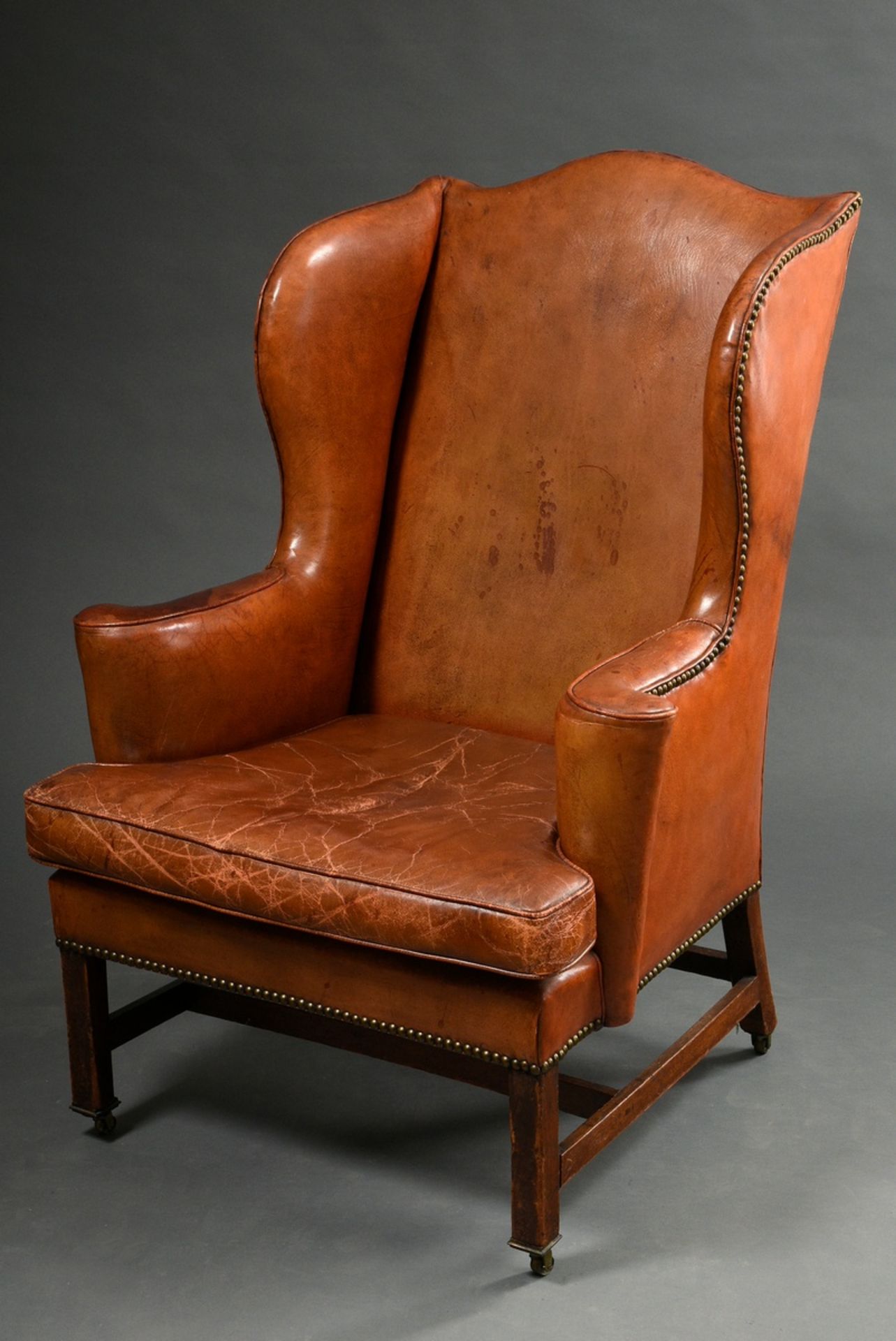 Englischer Ohrensessel, sog. „Grandfather Wingchair“, mit braunem Lederpolster und Messingnägeln au